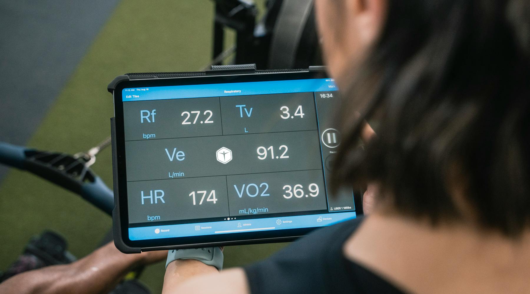 Adult man reviewing fitness metrics on a tablet during a workout session at the gym.
